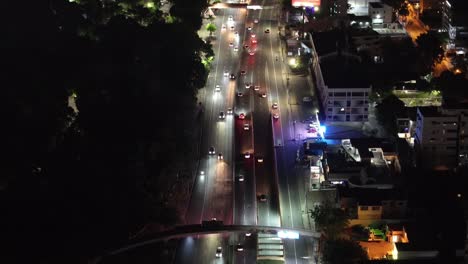 Luftaufnahme-Des-Nachtverkehrs-Auf-Der-Avenue-In-Einem-Wohnviertel-Von-Santo-Domingo,-Dominikanische-Republik,-Mit-Blick-Auf-Das-Stadtbild