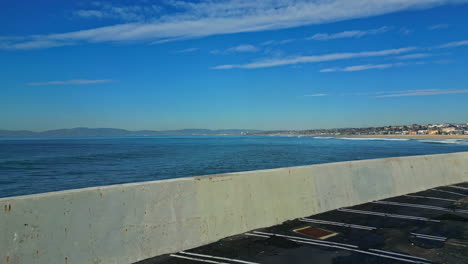 Drone-Aéreo-Sobre-La-Pared-Del-Aparcamiento-De-King-Harbor-Con-Vistas-Al-Océano-Pacífico-En-Manhattan-Beach-En-California