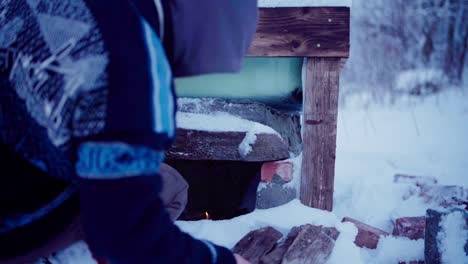 The-Man-is-Adding-Small-Pieces-of-Firewood-to-Heat-the-DIY-Hot-Tub---Close-Up