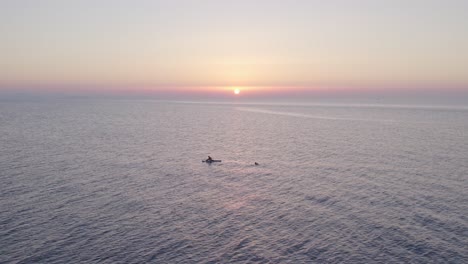 Vista-Aérea-Del-Barco-En-El-Mar-En-Calma-Con-Gente-Durante-La-Puesta-De-Sol,-Cefalu,-Sicilia,-Italia