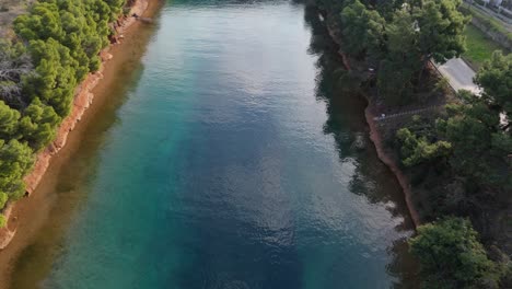 Luftaufnahme-Des-Erstaunlichen-Potidea-Kanals,-Der-Von-Xerxes-Erbaut-Wurde,-Einer-Küstenstadt-In-Griechenland,-Chalkidiki,-Mit-Kristallklarem-Grünem-Und-Blauem-Wasser-Der-Ägäis