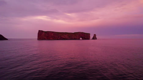 Drone-lateral-tracking-shot-of-Percé-Rock-during-a-cloudy-sunset