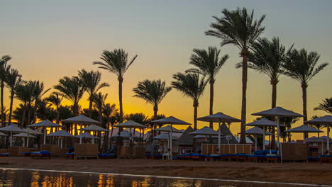 Una-Puesta-De-Sol-Naranja-Detrás-De-Las-Palmeras-En-Una-Playa-Tropical