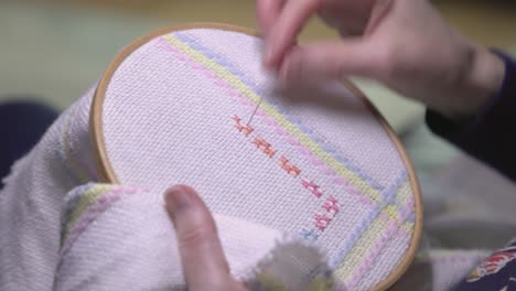 Close-up-shot-of-a-woman-making-patterns-on-a-cross-stitch-baby-blanket