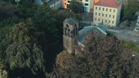 Eine-Historische-Kirche-Inmitten-üppiger-Bäume-In-Einer-Städtischen-Umgebung,-Tageslicht,-Luftaufnahme