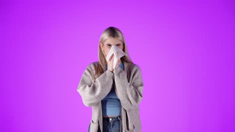 Woman-with-hay-fever-sneezes-into-napkin,-portrait-isolated-purple-background