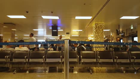 Malta-International-Airport,-a-row-of-empty-waiting-seats-and-unidentified-passengers-behind