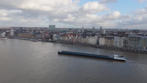 Aerial-Panning-Shot-of-Long-Ocean-Liner-Approaching-Bridge-in-Residential-Germany