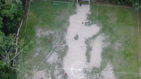 Vista-Aérea-De-Drones-En-Perú-Vista-Superior-En-La-Selva-Amazónica-Que-Muestra-A-Niños-Jugando-Al-Fútbol-En-Una-Cancha-De-Césped