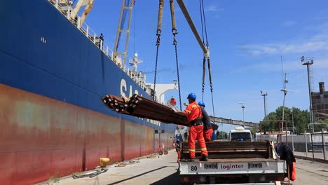 Workers-in-safety-gear-loading-cargo-on-ship-in-sunny-Argentine-port,-steady-shot