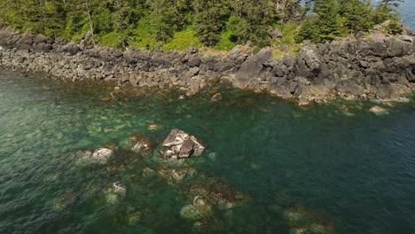 Aerial-Drone-Shot-Hovering-Over-Waters-Edge-with-Rocky-Coastline-near-Sandpit,-Grey-Bay,-Canada