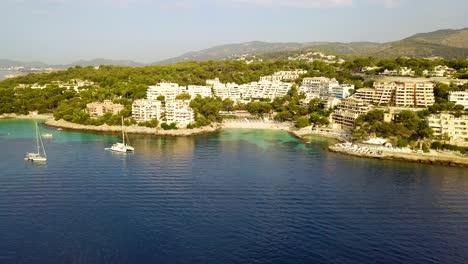 Retreating-drone-shot-of-the-beachfront-of-Playa-Illetas,-off-the-coast-of-Mallorca-in-Palma-Island,-in-Spain