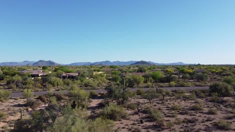Houses-in-desert-during-hot,-dry-morning-sunrise-with-cacti-and-desert-flora