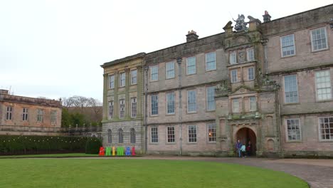 Historisches-Lyme-House-In-Cheshire-Mit-Grünem-Rasen-Unter-Bewölktem-Himmel,-Bunte-Schilder-Im-Vordergrund