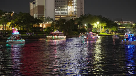 Barcos-Coloridos-Adornados-Con-Adornos-Navideños-Y-Luces-Desfilando-Por-El-Río-En-Tampa,-Florida,-Por-La-Noche