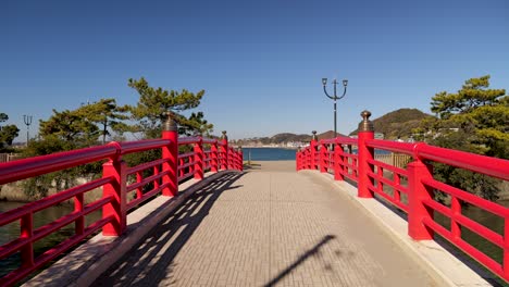 Typical-red-Japanese-wooden-bridge-leading-out-to-ocean-on-blue-sky-sunny-day