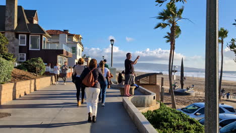 People-walking-on-the-Manhattan-beach-promenade,-sunset-in-Los-Angeles,-USA