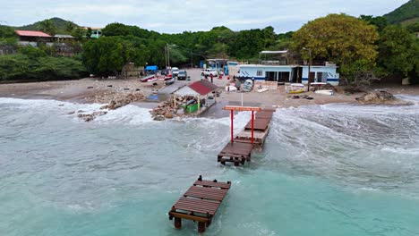 Broken-wooden-pier-dock-stands-in-rocky-turbulent-ocean-as-waves-crash-on-boat-launch-ramp