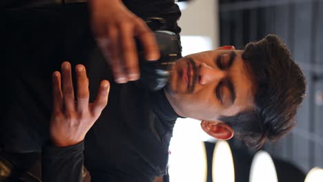 Handsome-Indian-guy-drinking-coffee-from-black-mug,-vertical-view