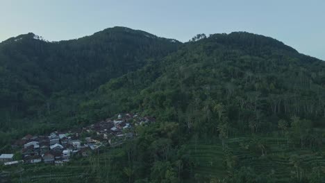 Aerial-view-of-village-on-the-foot-of-forested-hill-in-the-morning