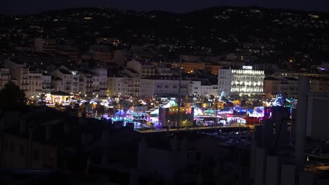 Town-fair-seen-at-night-with-attractions-and-rides-with-Splendid-Hotel-right,-Wide-handheld-shot