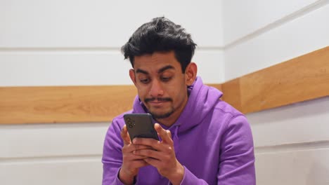 Junger-Mann-Aus-Sri-Lanka-Benutzt-Sein-Smartphone,-Während-Er-Im-Büro-Darauf-Wartet,-An-Die-Reihe-Zu-Kommen