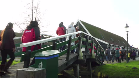 Large-group-of-tourist-walking-over-a-little-bridge-in-overcrowded-Zaanse-Schans