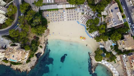 Playa-illetas-with-clear-waters-and-beachgoers-in-mallorca,-spain,-during-summer,-aerial-view
