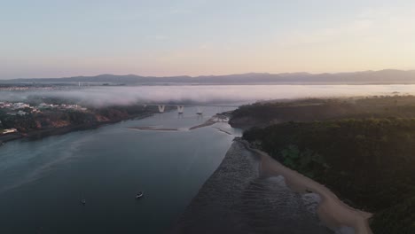 Dünne-Wolken-Bedecken-Eine-Brücke-In-Der-Nähe-Einer-Stadt-Am-Flussufer-In-Portugal