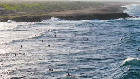 Surfers-wait-in-lineup-sitting-on-board-as-large-waves-roll-in-sets