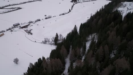 Aerial-reveal-of-snowy-race-track-remote-location-valley-near-dark-forest