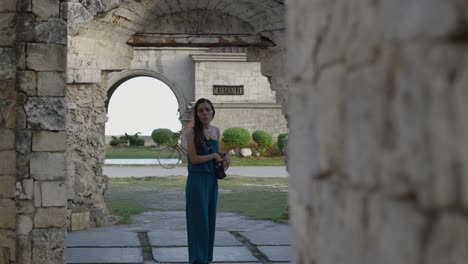 Mujer-Explorando-Las-Ruinas-De-Cuartel-En-Oslob,-Filipinas,-Enmarcadas-Por-Un-Arco-De-Piedra-A-La-Luz-Del-Día.