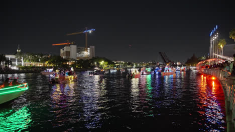 Weitwinkelaufnahme-Von-Weihnachtsbeleuchtung-Auf-Booten-In-Der-Wasserstraße-Mit-Familien,-Die-Die-Parade-Beobachten