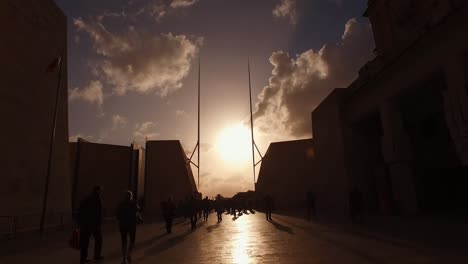 Neues-Stadttor-Von-Valletta-In-Malta-Während-Des-Sonnenuntergangs-Und-Silhouetten-Der-Passagiere,-Die-Auf-Der-Republic-Street-Spazieren