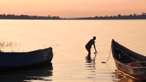 A-woman-collects-water-in-a-petrol-can-by-the-shore-of-Lake-Victoria-and-walks-out-of-frame