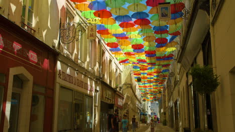 Idyllic-street-in-France-with-colorful-umbrellas-creating-shade-for-pedestrians