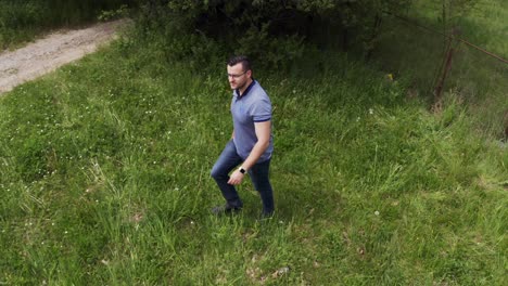 Retreating-drone-shot-moving-away-from-a-tourist-walking-in-a-field-in-the-outskirts-of-Tsarichina-Village-in-a-Bulgarian-countryside