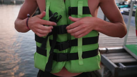 Young-anonymous-male-locking-life-vest-jacket-buckle-preparing-for-water-sport-lesson