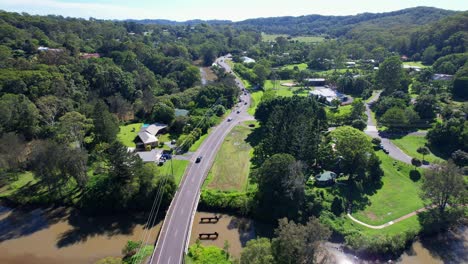 Vehicles-Traveling-On-Road-Between-Lush-Vegetation-In-Currumbin-Valley,-Gold-Coast,-QLD,-Australia---Drone-Shot