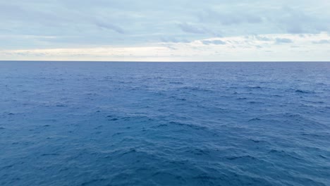 Langsamer-Luftflug-über-Offenem-Ozeanwasser-Mit-Wolken-Am-Horizont,-Faszinierende-Langsame-Bewegung-Zum-Horizont