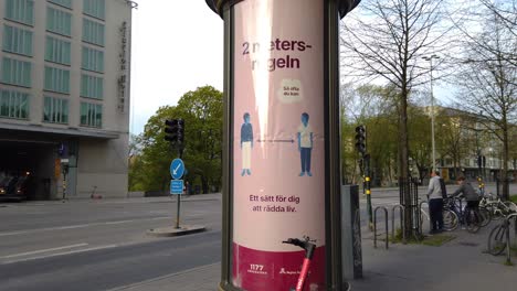 Coronavirus-info-on-rotating-sign-on-street-in-Stockholm,-traffic-in-background