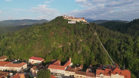 Ciudad-De-Rasnov-Y-Castillo-Fortaleza-En-La-Cima-De-Una-Colina-En-Los-Cárpatos,-Rumania---Antena-4k