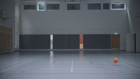 Static-view-of-basketball-rolling-in-gymansium-empty