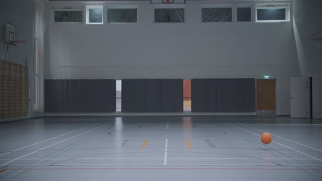 Vista-Estática-Del-Baloncesto-Rodando-En-El-Gimnasio-Vacío.