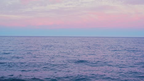 Purple-sunset-sky-and-rocky-shore-of-Tenerife-island,-tilt-up-view