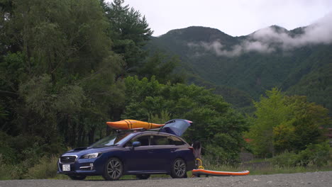 A-blue-family-car-is-parked,-where-a-child-is-seen-fixing-her-kayak,-ready-for-a-pleasant-day-ahead