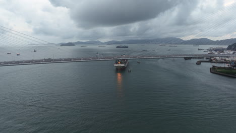 Suspension-bridge-with-Large-container-vessel-approaching-the-background---drone-orbiting-shot