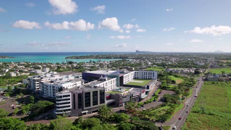 La-croisette-in-mauritius,-modern-buildings-alongside-lush-greenery,-under-clear-blue-skies,-aerial-view