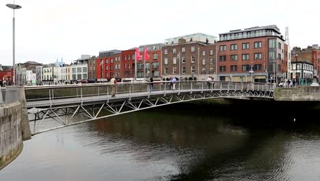 Pedestrians-crossing-a-bridge-spanning-the-Liffey-River