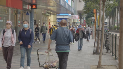 People-walking-on-street-in-Hong-Kong,-some-people-wear-face-masks